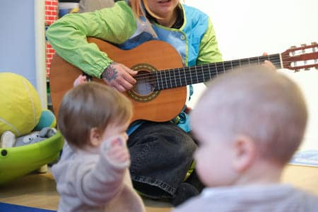 Photo d'une accueillante qui joue de la guitare pour les enfants