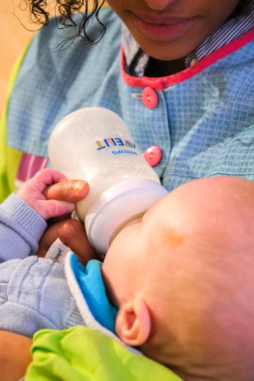 Photo d'une accueillante qui donne le biberon à un enfant